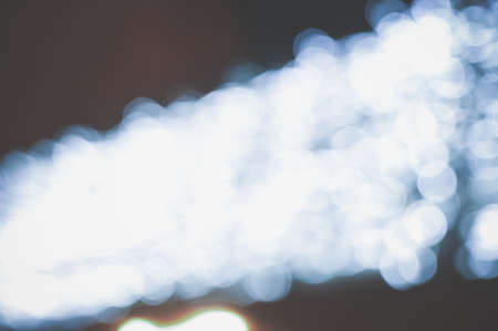 Blurry defocused festive glitter bokeh, shiny lights illumination texture backgroundの写真素材