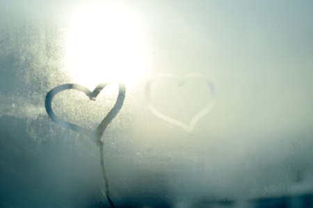 2 love hearts painted on a misted glass window background. Close up photo of lovely emotional mood drawの写真素材