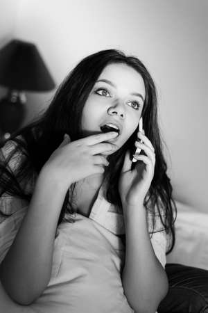 Attractive woman talking on phone relaxing in light bed background. Closeup portraitの写真素材