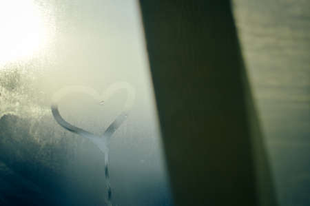Closeup on love heart inscription over sweaty window glass background. Emotional solar creative symbol conceptの写真素材