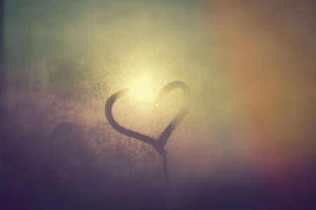 Closeup on love heart inscription over sweaty window glass background. Emotional solar creative symbol conceptの写真素材