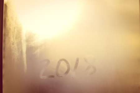 Closeup image of the 2018 inscription sign on condensated glass blurred translucent effect window. Creative monochrome foggy copyspaceの写真素材