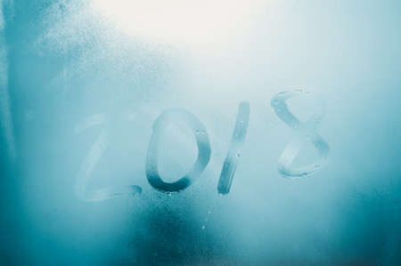 Closeup image of the 2018 inscription sign on condensated glass blurred translucent effect window. Creative monochrome foggy copyspaceの写真素材