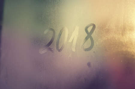 Closeup image of the 2018 inscription sign on condensated glass blurred translucent effect window. Creative monochrome foggy copyspaceの写真素材