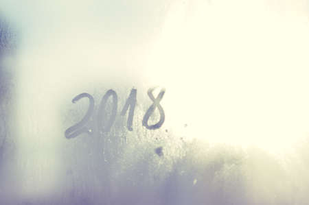 Closeup image of the 2018 inscription sign on condensated glass blurred translucent effect window. Creative monochrome foggy copyspaceの写真素材