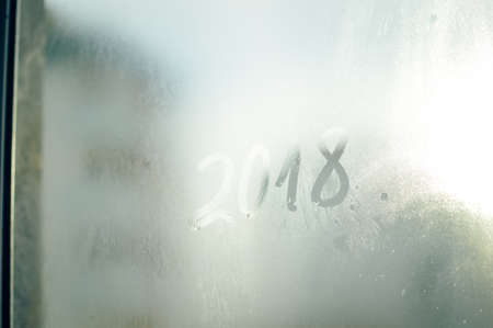 2018 painted on a misted glass window background. Close up photo of New Year draw