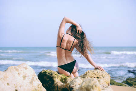 Back view of attractive young, fit and sexy woman in swimsuit on sunny outdoor background. Joyful beach holiday fun rest. Relaxation, meditation and contemplationの写真素材