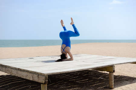 Back view of woman sport stretching over the blue sea outdoor sunny backgroundの写真素材