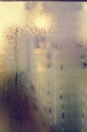 Abstract blurry drops on a transparent rainy window foggy outdoors background texture. Environmental...