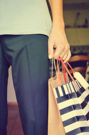 Shopping experience. Close up photography on caucasian male hand holding purchases, light copy space background. Person buying joyful lifestyle.の写真素材