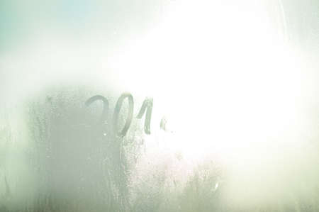 2018 sign draw on wet condensated window glass, blurred texture abstract background, close up view photoの写真素材