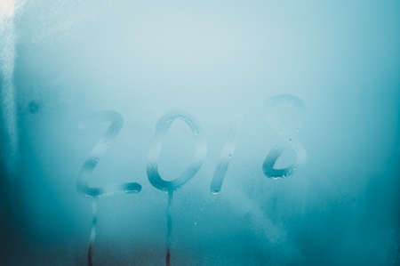 2018 sign draw on wet condensated window glass, blurred texture abstract background, close up view photoの写真素材