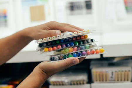 Man choosing buying stationery in store preparing for first day in school. Closeup on buyer hands holding goods. Busy blurred shopping indoors backgroundの写真素材