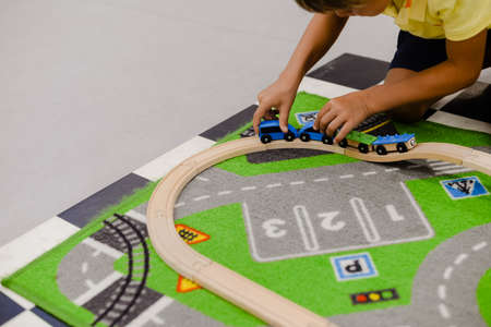 Closeup on children playing with wooden toy train, build railroad on home or school backgroundの写真素材