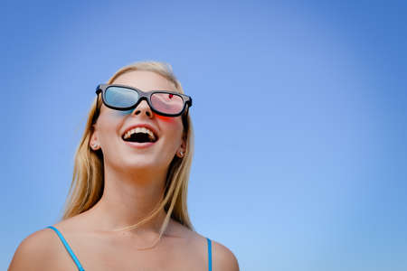 Joyful excited lovely attractive woman is watching 3 D movie. Excitement beauty young lady over light background. Funky enjoyment, surprised amazing experience. People having fun leisure lifestyleの写真素材