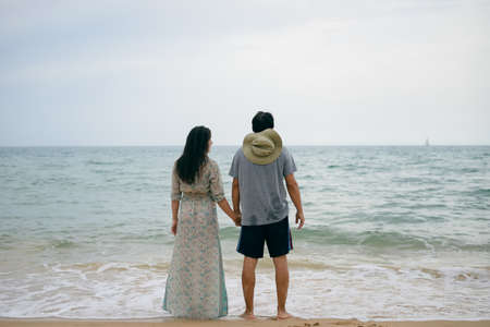 Lovely couple having fun on the beach outdoors background. Back view of healthy people, excitement...