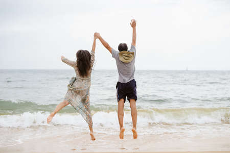 Lovely couple having fun on the beach outdoors background. Back view of healthy people, excitement and amazement emotional freedom leisure. Travel vacation attractive enjoyment lifestyle.の写真素材
