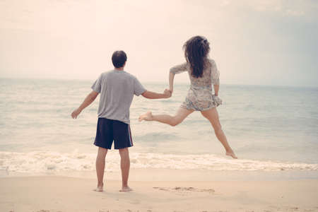 Lovely couple having fun on the beach outdoors background. Back view of healthy people, excitement and amazement emotional freedom leisure. Travel vacation attractive enjoyment lifestyle.の写真素材