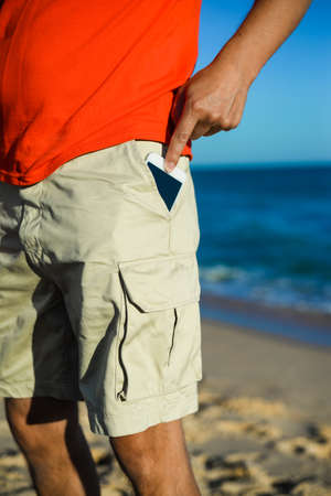 Back view of man using phone with blank screen on sunny outdoorsの写真素材