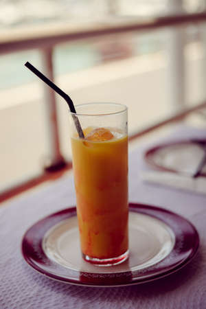 Glass of refreshing cool mango-lassi sweet Indian drink on restaurant table light backgroundの写真素材