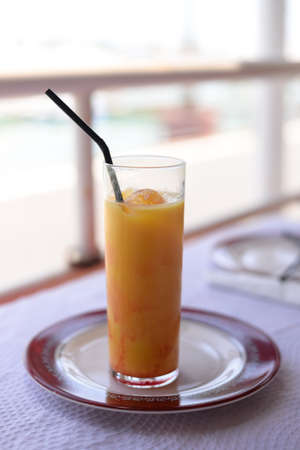 Glass of refreshing cool mango-lassi sweet Indian drink on restaurant table light backgroundの写真素材