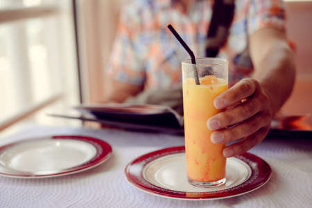 Glass of refreshing cool mango-lassi sweet Indian drink on restaurant table light backgroundの写真素材