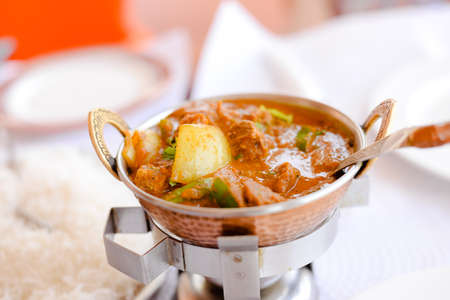 Closeup on Indian speciality curry dish on light restaurant table background. Traditional maincourse...