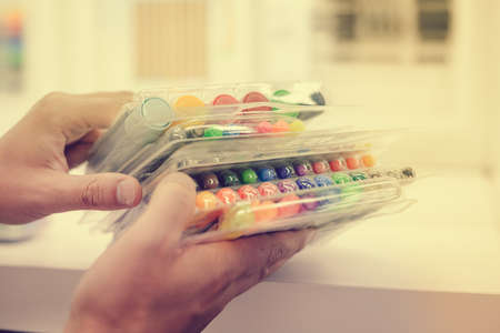 Back to school or work. Close up on human hands buying stationary, side view. Closeup of person holding purchase over shopping mall department backgroundの写真素材