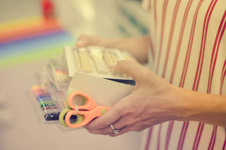 Back to school or work. Close up on human hands buying stationary, side view. Closeup of person holding purchase over shopping mall department backgroundの写真素材