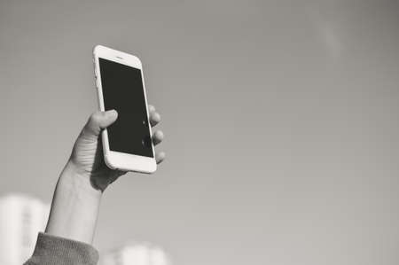 Happy cute Santa child holding mobile smartphone showing blank display for your text message on light sky background. Happiness shopping time and electronic education lifestyle. Close up photoの写真素材