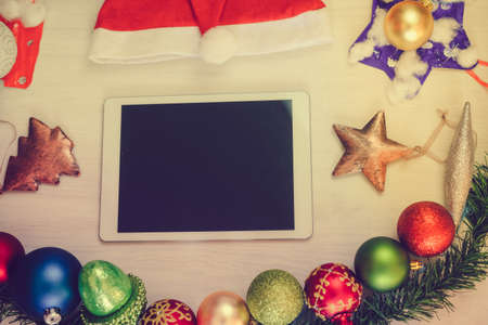 Top view of tablet computer and Christmas decor on wooden background. Mock up closeup photography. Modern technology connection, shopping delivery service, social network, festive happy busy timeの写真素材