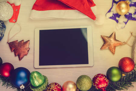 Top view of tablet computer and Christmas decor on wooden background. Mock up closeup photography. Modern technology connection, shopping delivery service, social network, festive happy busy timeの写真素材