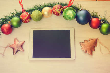 Top view of tablet computer and Christmas decor on wooden background. Mock up closeup photography. Modern technology connection, shopping delivery service, social network, festive happy busy timeの写真素材