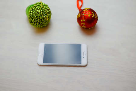 Top view of mobile phone and Christmas decor on wooden background. Mock up closeup photography. Modern technology connection, shopping delivery service, social network, festive happy busy timeの写真素材