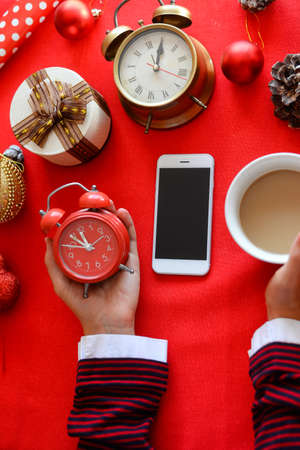 Top side view of hands using mobile phone on red background with Christmas gifts. Xmas Happy New...