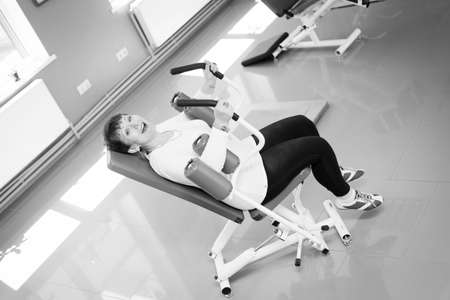 Black and white photography of happy smiling pretty woman doing fitness exercises in health clubの写真素材