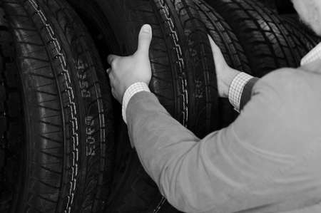 Black and white photography of person hands choosing a car tire. closeupの写真素材
