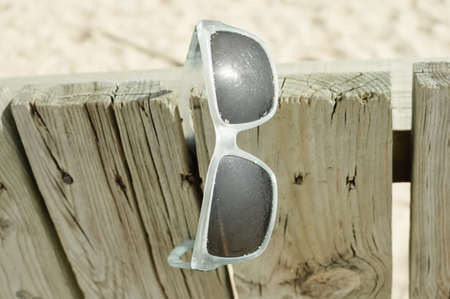 Weathered sunglasses on the beach, close up design. Touristic seaside shore view on natural wooden background for wallpaper, tour destination advertisimentの写真素材