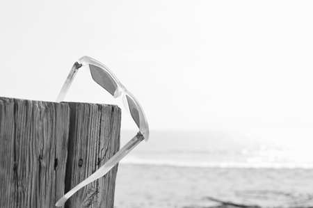 Weathered sunglasses on the beach, close up design. Touristic seaside shore view on natural wooden background for wallpaper, tour destination advertisimentの写真素材