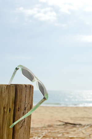 Weathered sunglasses on the beach, close up design. Touristic seaside shore view on natural wooden background for wallpaper, tour destination advertisimentの写真素材