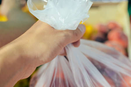 Close up on human hand holding chooses tomatoes food shop market backgroundの写真素材