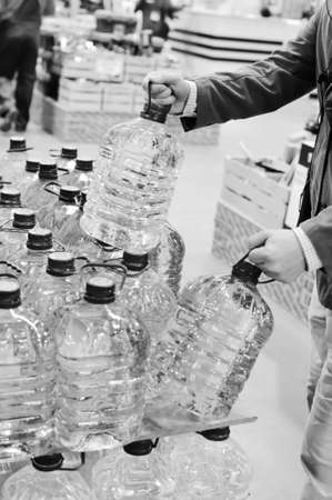 Black and white photography of person choosing buying bottles of waterの写真素材