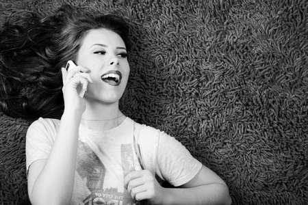 Black and white photography of sexy young beautiful woman relaxing and talking on mobile phone over copy spaceの写真素材