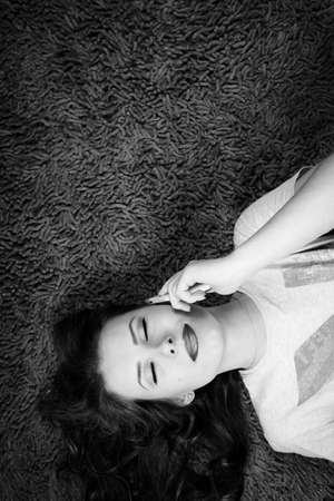 Black and white photography of young beautiful woman talking on mobile phone with eyes closedの写真素材