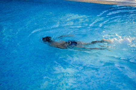 Defocused blurry underwater swimmer, recreational relax in swimming pool sunny outdoors background....