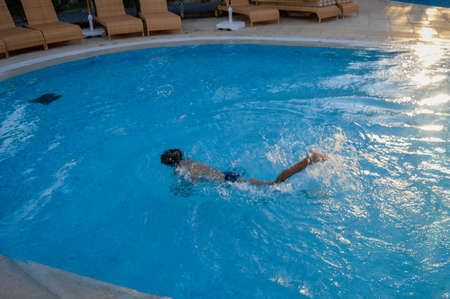 Defocused blurry underwater swimmer, recreational relax in swimming pool sunny outdoors background....