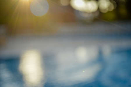 Defocused blurry recreational holiday swimming pool sunny tropical background. Unfocused blurred outdoors for having fun on travel vacation summertime relaxの写真素材
