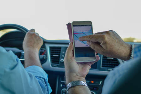 Closeup on person holding using mobile phone on the car interior background, modern smart computer apps solution and online networkの写真素材