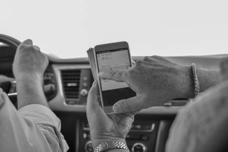Closeup on person holding using mobile phone on the car interior background, modern smart computer apps solution and online networkの写真素材
