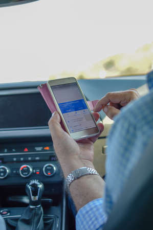 Closeup on person holding using mobile phone on the car interior background, modern smart computer apps solution and online networkの写真素材